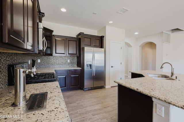 13145 Hazy, El Paso, TX 79938 - kitchen featuring appliances with stainless steel finishes, dark brown cabinets, light wood finished floors, light stone counters, and decorative backsplash