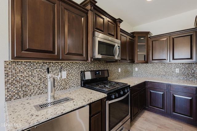 13145 Hazy, El Paso, TX 79938 - kitchen featuring stainless steel appliances, dark brown cabinetry, light stone counters, and decorative backsplash