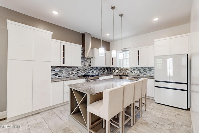 337 Vin Almoradi Ct, El Paso, TX 79912 - kitchen with a breakfast bar, freestanding refrigerator, wall chimney exhaust hood, marble finish floor, and hanging light fixtures