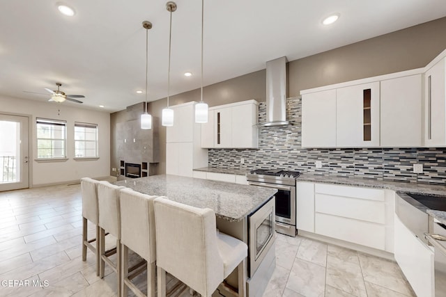 337 Vin Almoradi Ct, El Paso, TX 79912 - kitchen with a ceiling fan, appliances with stainless steel finishes, wall chimney range hood, and tasteful backsplash
