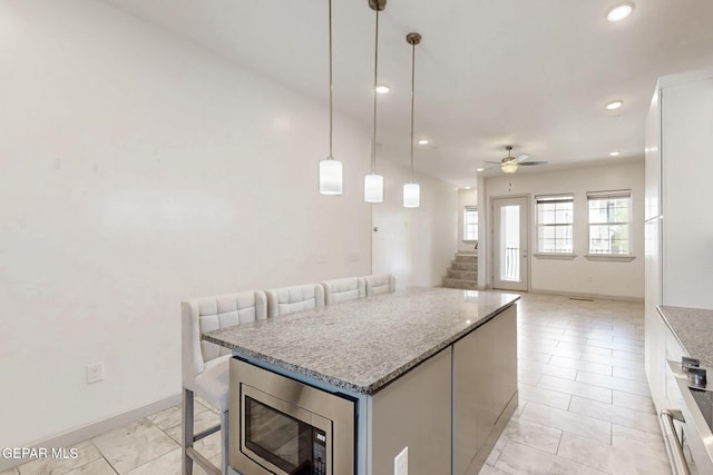 337 Vin Almoradi Ct, El Paso, TX 79912 - kitchen featuring stainless steel microwave, ceiling fan, white cabinetry, a kitchen island, and open floor plan