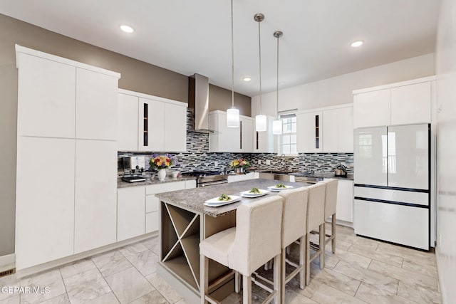 337 Vin Almoradi Ct, El Paso, TX 79912 - kitchen featuring decorative backsplash, a kitchen breakfast bar, wall chimney exhaust hood, marble finish floor, and freestanding refrigerator