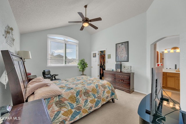 bedroom featuring lofted ceiling, a ceiling fan, arched walkways, light colored carpet, and a spacious closet