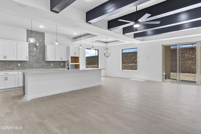 unfurnished living room with a sink, ceiling fan, light wood-type flooring, and beam ceiling