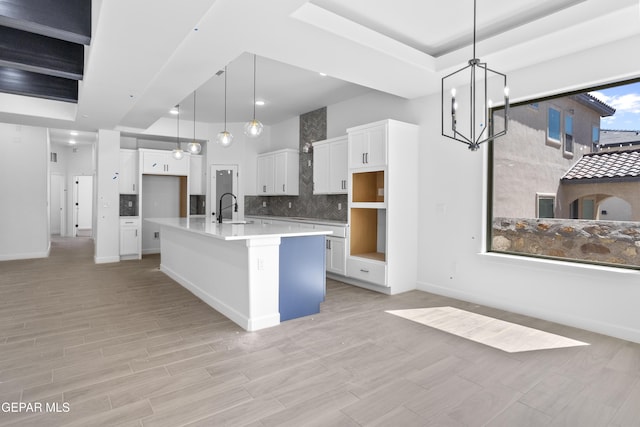 kitchen featuring a sink, decorative backsplash, an inviting chandelier, and light wood finished floors
