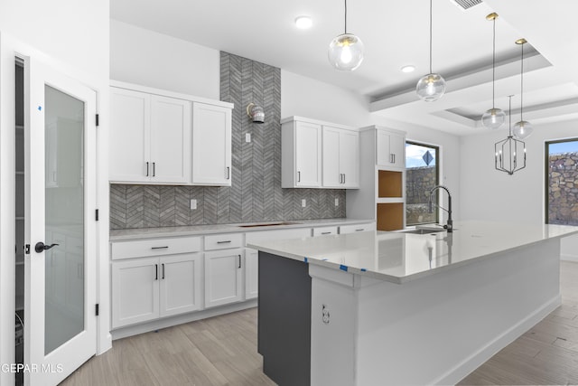 kitchen featuring backsplash, a wealth of natural light, a sink, and light wood-style floors