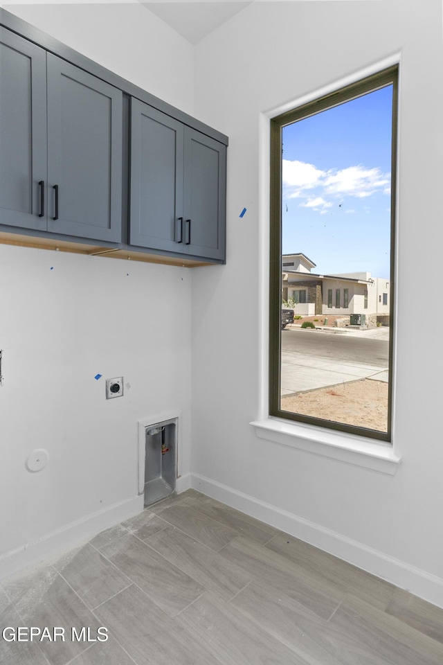 washroom featuring cabinet space, electric dryer hookup, and baseboards