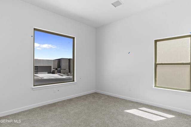 carpeted spare room featuring baseboards and visible vents