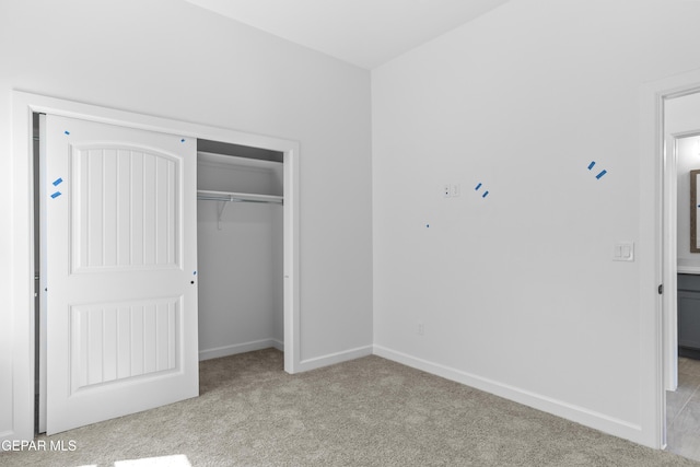 unfurnished bedroom with baseboards, light colored carpet, and a closet