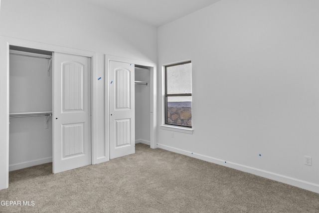 unfurnished bedroom featuring multiple closets, baseboards, and carpet floors
