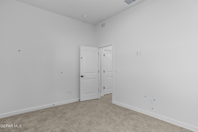 unfurnished room with baseboards, light colored carpet, and visible vents
