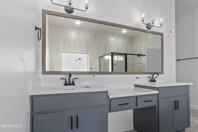 bathroom with a sink, a shower stall, double vanity, and a notable chandelier