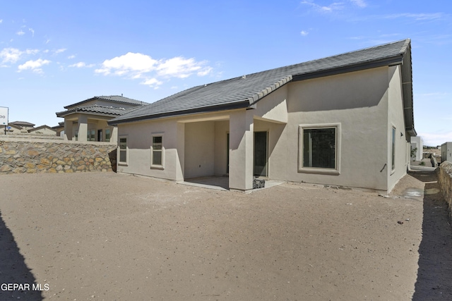 back of house featuring fence, stucco siding, a patio area, and a tiled roof