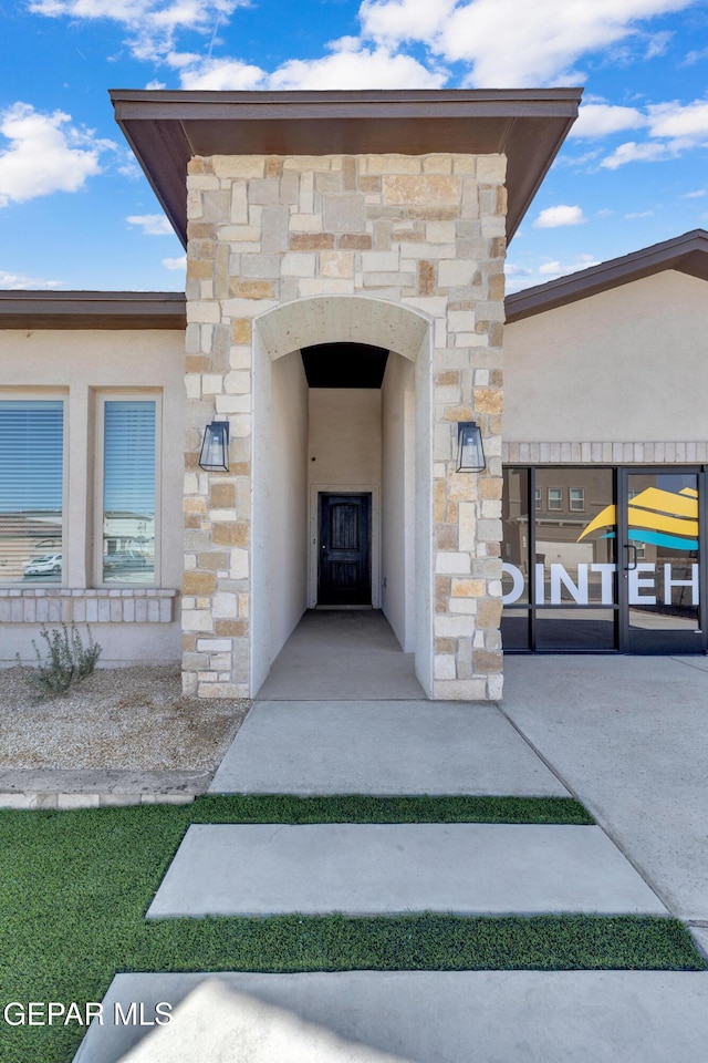 view of exterior entry featuring stucco siding and stone siding