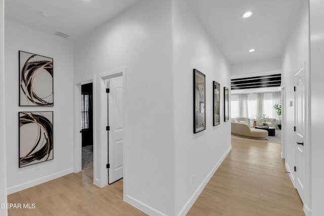 hallway featuring light wood-style floors, baseboards, recessed lighting, and visible vents