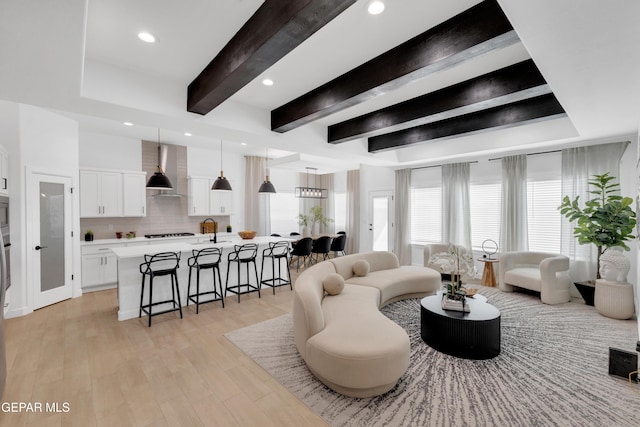living room with recessed lighting, beam ceiling, and light wood-style flooring