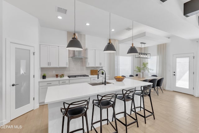 kitchen with visible vents, a kitchen breakfast bar, gas cooktop, a sink, and backsplash