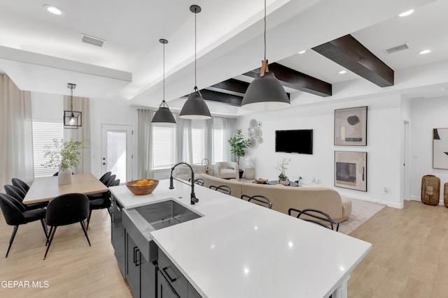 kitchen with light wood-style floors, light countertops, a sink, and visible vents