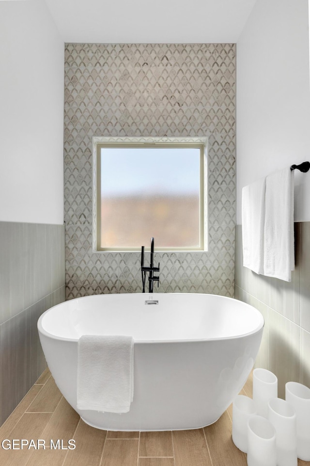 bathroom with wallpapered walls and a freestanding tub