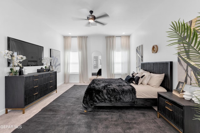 carpeted bedroom featuring arched walkways, baseboards, and a ceiling fan