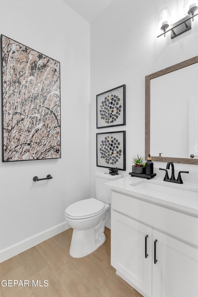 bathroom with vanity, baseboards, toilet, and wood finished floors