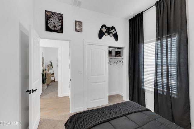 bedroom featuring visible vents, light wood finished floors, baseboards, and a closet