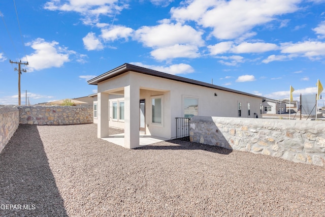 rear view of house featuring a fenced backyard, a patio, and stucco siding