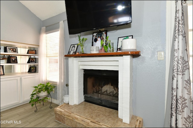 details featuring a fireplace, a textured wall, and wood finished floors