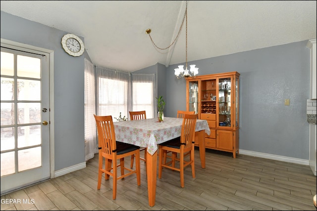 dining space featuring an inviting chandelier, baseboards, light wood-style flooring, and lofted ceiling