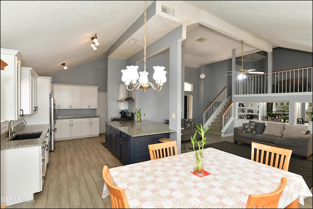 dining area featuring stairway, a textured ceiling, ceiling fan with notable chandelier, and light wood-type flooring