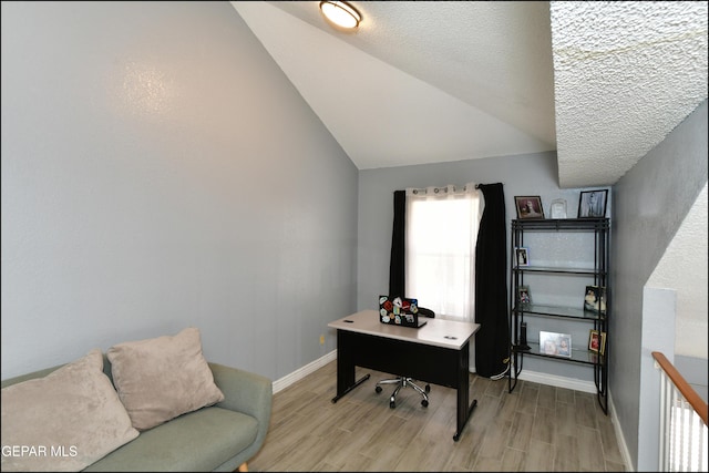 office area featuring baseboards, lofted ceiling, and light wood-type flooring
