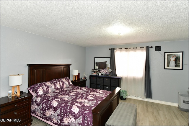 bedroom with a textured ceiling and light wood-style floors