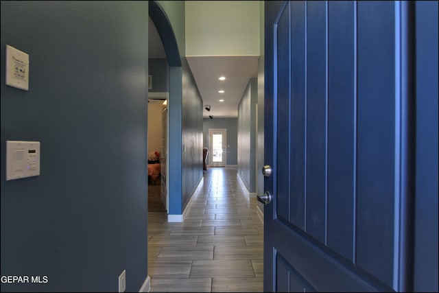 hallway featuring baseboards, recessed lighting, and arched walkways