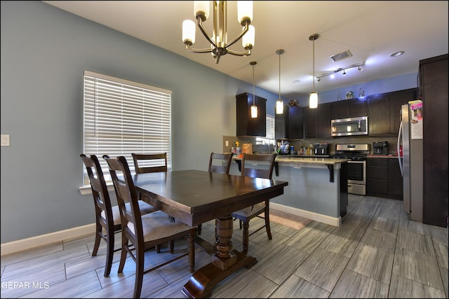 dining room with a chandelier, wood tiled floors, and baseboards