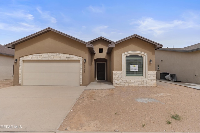 view of front of home featuring stucco siding, stone siding, cooling unit, an attached garage, and driveway