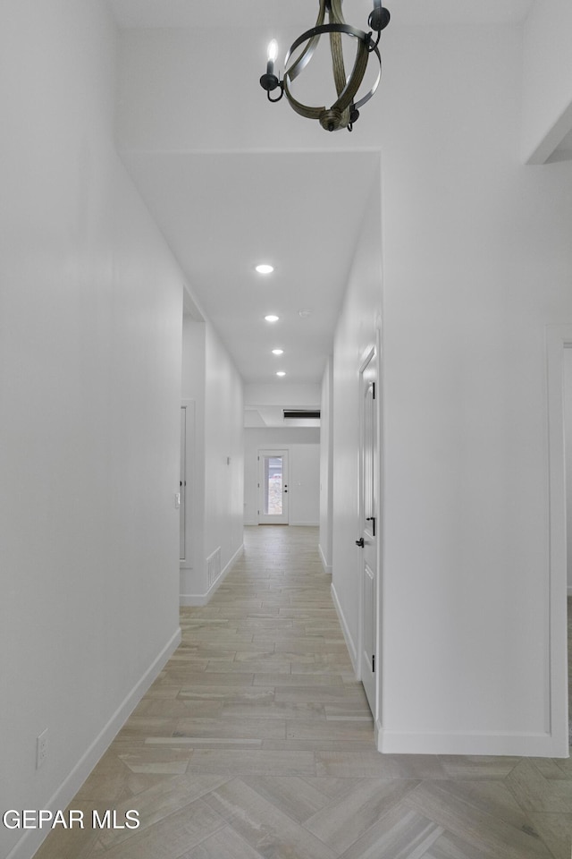 hall featuring a chandelier, baseboards, recessed lighting, and light wood-style flooring