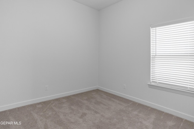 carpeted spare room featuring baseboards