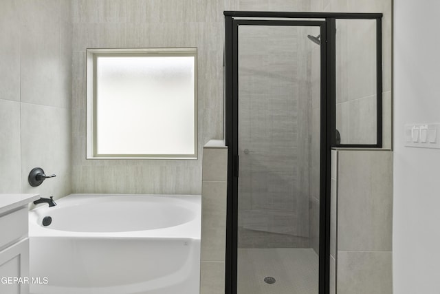 bathroom featuring plenty of natural light, a stall shower, a bath, and vanity