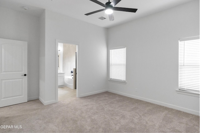 unfurnished bedroom with light carpet, baseboards, and ensuite bath