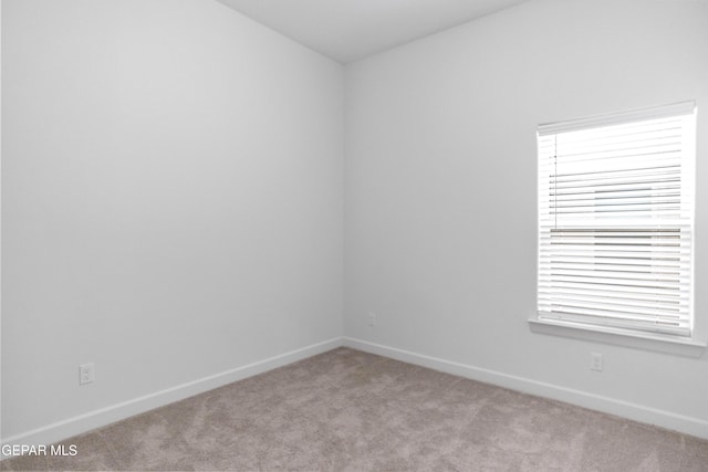 unfurnished room featuring light colored carpet and baseboards