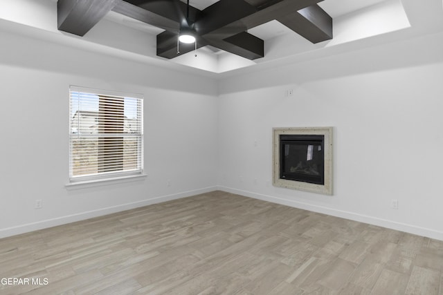 unfurnished room with wood finished floors, a fireplace, ceiling fan, baseboards, and beamed ceiling