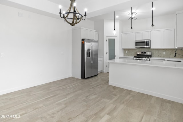 kitchen with stainless steel appliances, a chandelier, backsplash, light countertops, and light wood-style flooring