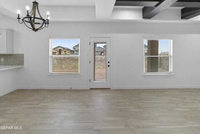 entryway with a chandelier, healthy amount of natural light, beam ceiling, light wood-style floors, and baseboards