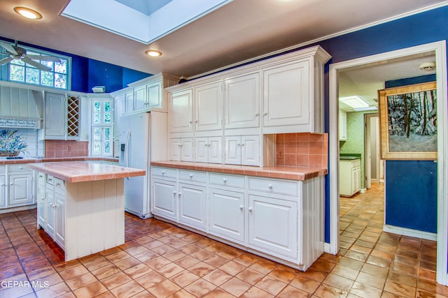 6041 Torrey Pines Dr, El Paso, TX 79912 - kitchen with white fridge with ice dispenser, white cabinets, tile countertops, and tasteful backsplash
