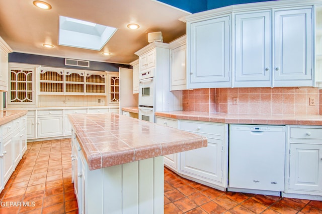 6041 Torrey Pines Dr, El Paso, TX 79912 - kitchen with tasteful backsplash, visible vents, tile countertops, white appliances, and a skylight
