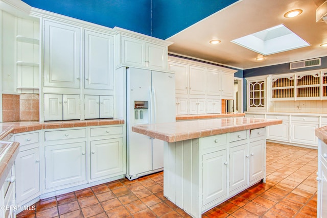 6041 Torrey Pines Dr, El Paso, TX 79912 - kitchen featuring white cabinetry, white refrigerator with ice dispenser, recessed lighting, tile countertops, and a skylight