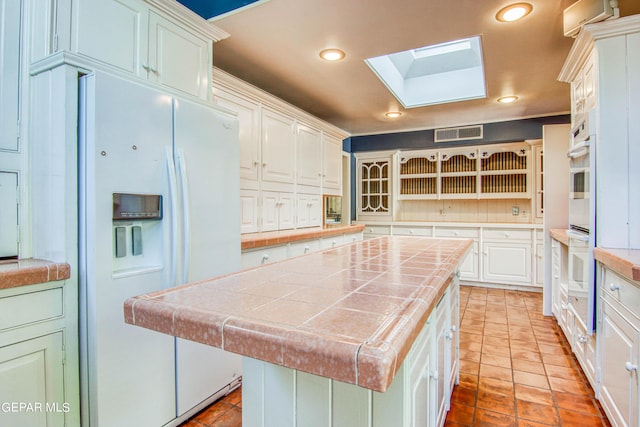 6041 Torrey Pines Dr, El Paso, TX 79912 - kitchen featuring tile counters, visible vents, recessed lighting, white appliances, and a skylight