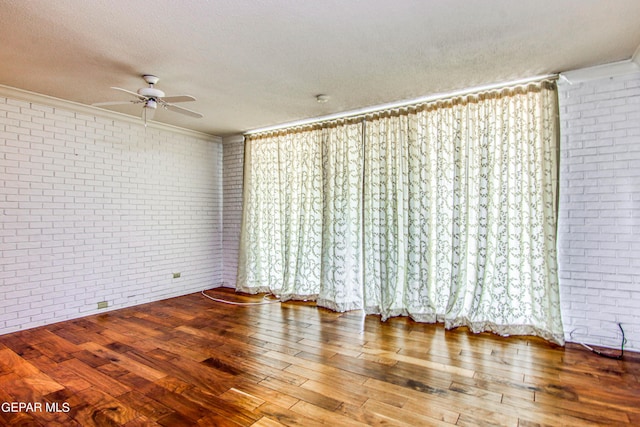 6041 Torrey Pines Dr, El Paso, TX 79912 - empty room featuring a textured ceiling, wood-type flooring, brick wall, ornamental molding, and a ceiling fan