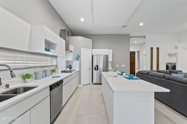 1725 Eased St, El Paso, TX 79928 - kitchen with white cabinetry, appliances with stainless steel finishes, a kitchen island, washer and clothes dryer, and wall chimney exhaust hood