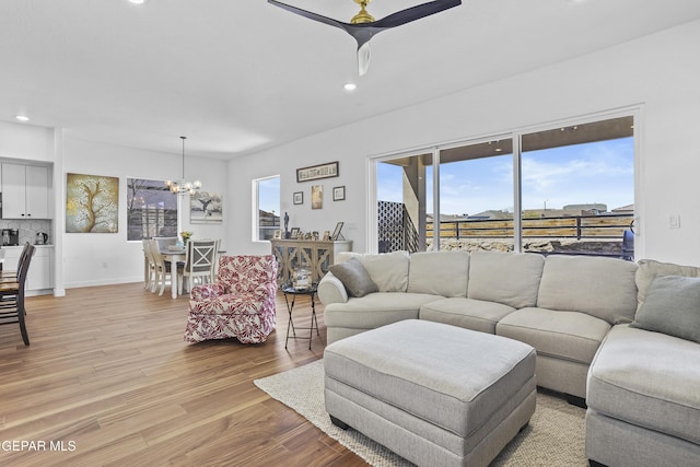 living area featuring baseboards, recessed lighting, ceiling fan with notable chandelier, and light wood finished floors